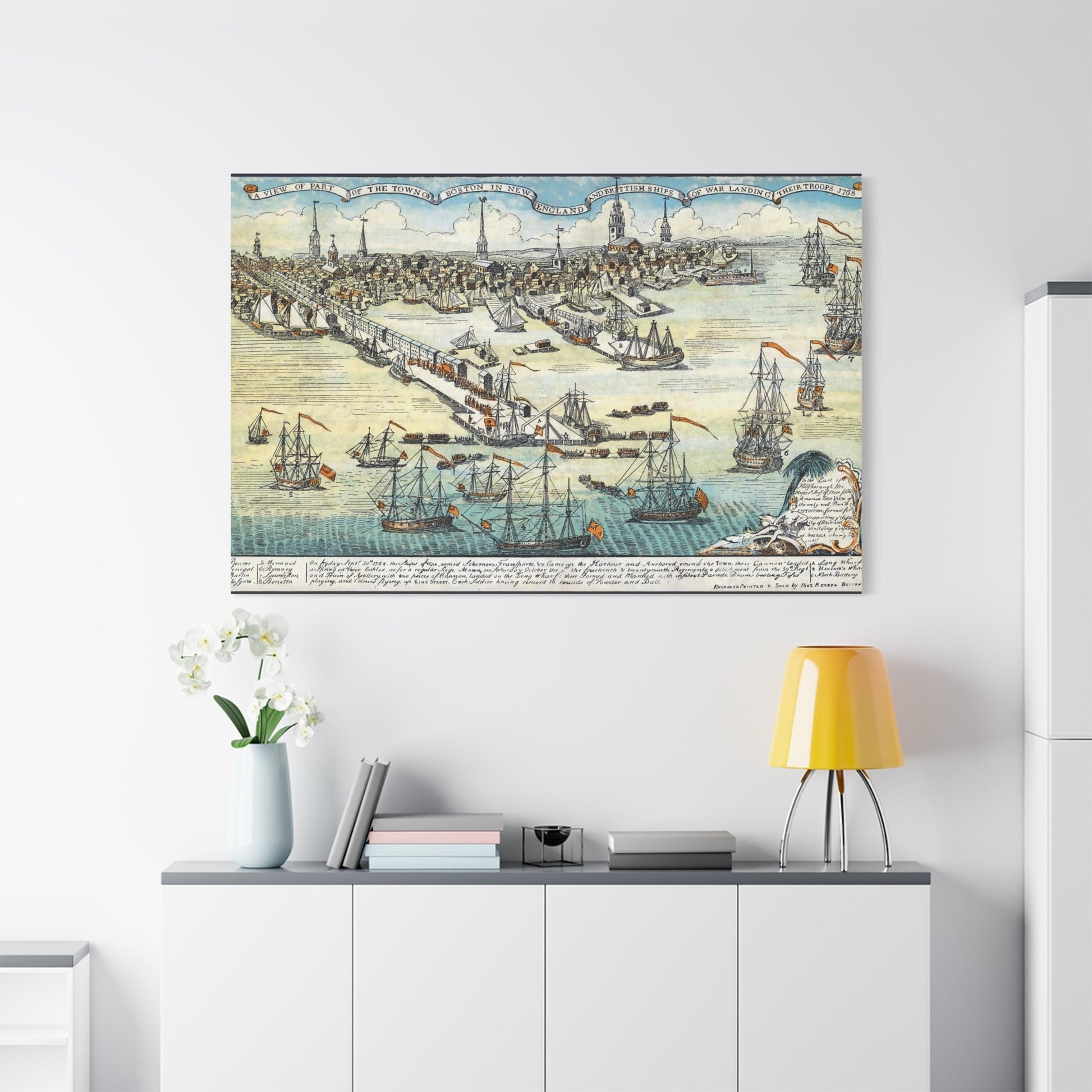 Vintage nautical wall art canvas print featuring sailing ships and a historic map above a modern sideboard with books, flowers, and a lamp in a minimalist room.
